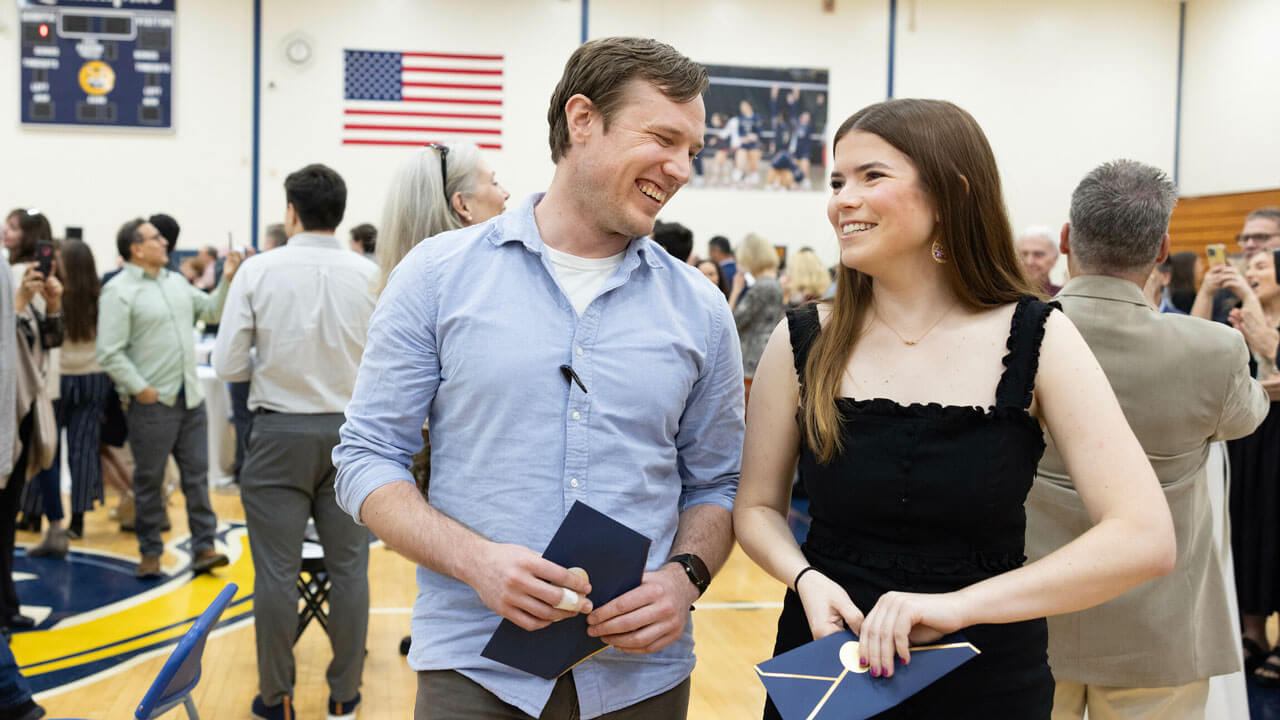 Sammer Dia and Ryan Morris smile together as they hold their navy-colored Match envelopes