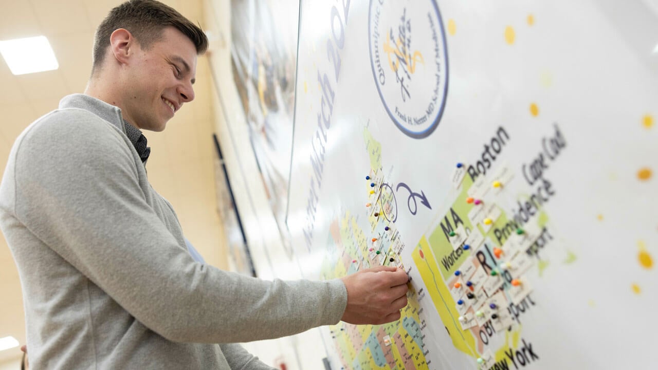 Derek Paradis pins his name to Washington D.C. on a map of the nation to signify his match