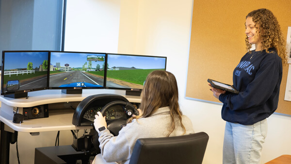 OT student observing a young woman on the driving simulator
