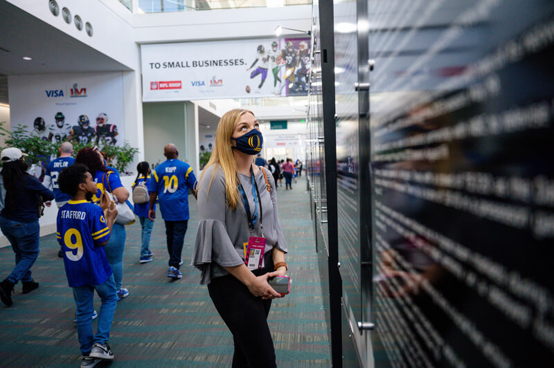 A student wearing press credentials stops to read a wall in the LA Convention Center