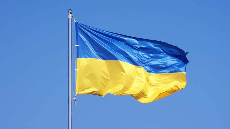 The Ukraine flag flies in front of a clear blue sky