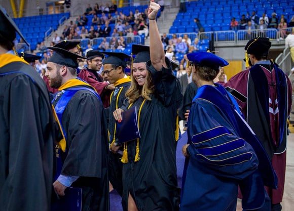 Woman raises hand in the air during commencement