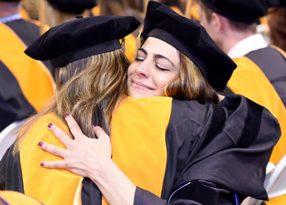 Two students hugging at graduation