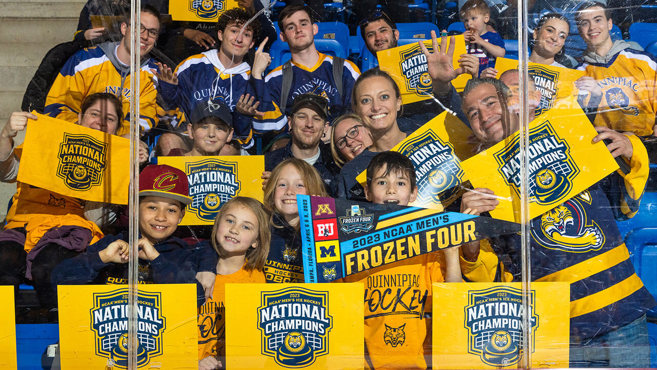 Fans in the stands holding 2023 NCAA Men's Frozen Four signs