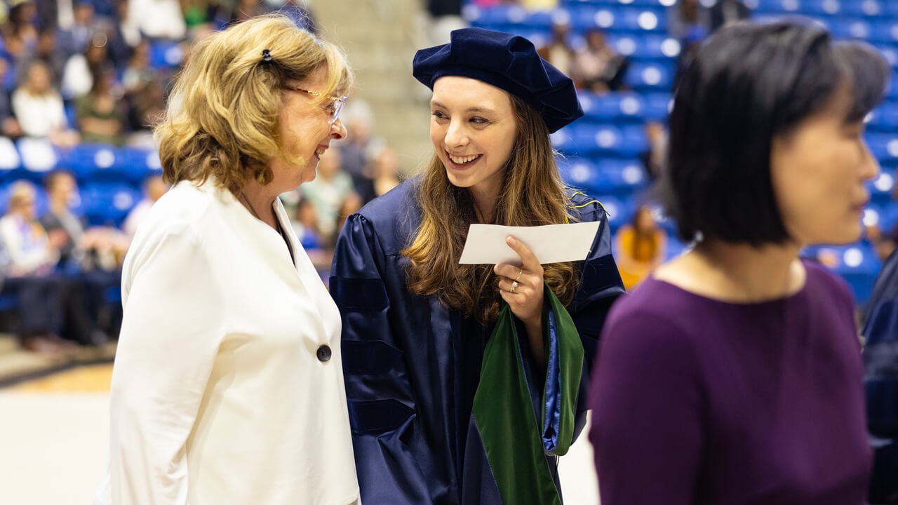 A graduate and her guest smile at each other