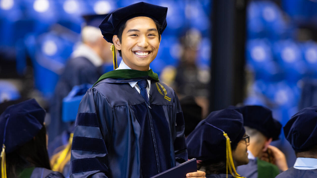 Medicine graduate smiling ear to ear, excited to be hooded during Medicine Commencement