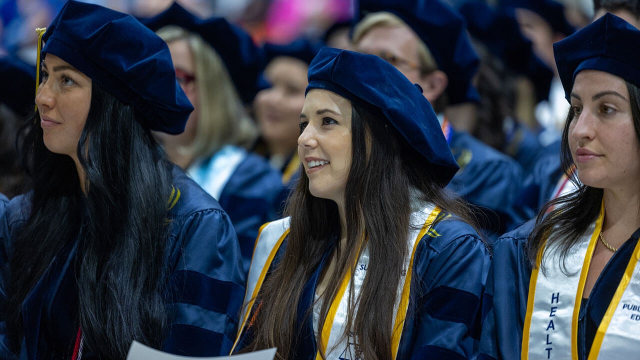 Class of 2024 law graduate listens intently to a guest speaker during the commencement ceremony.