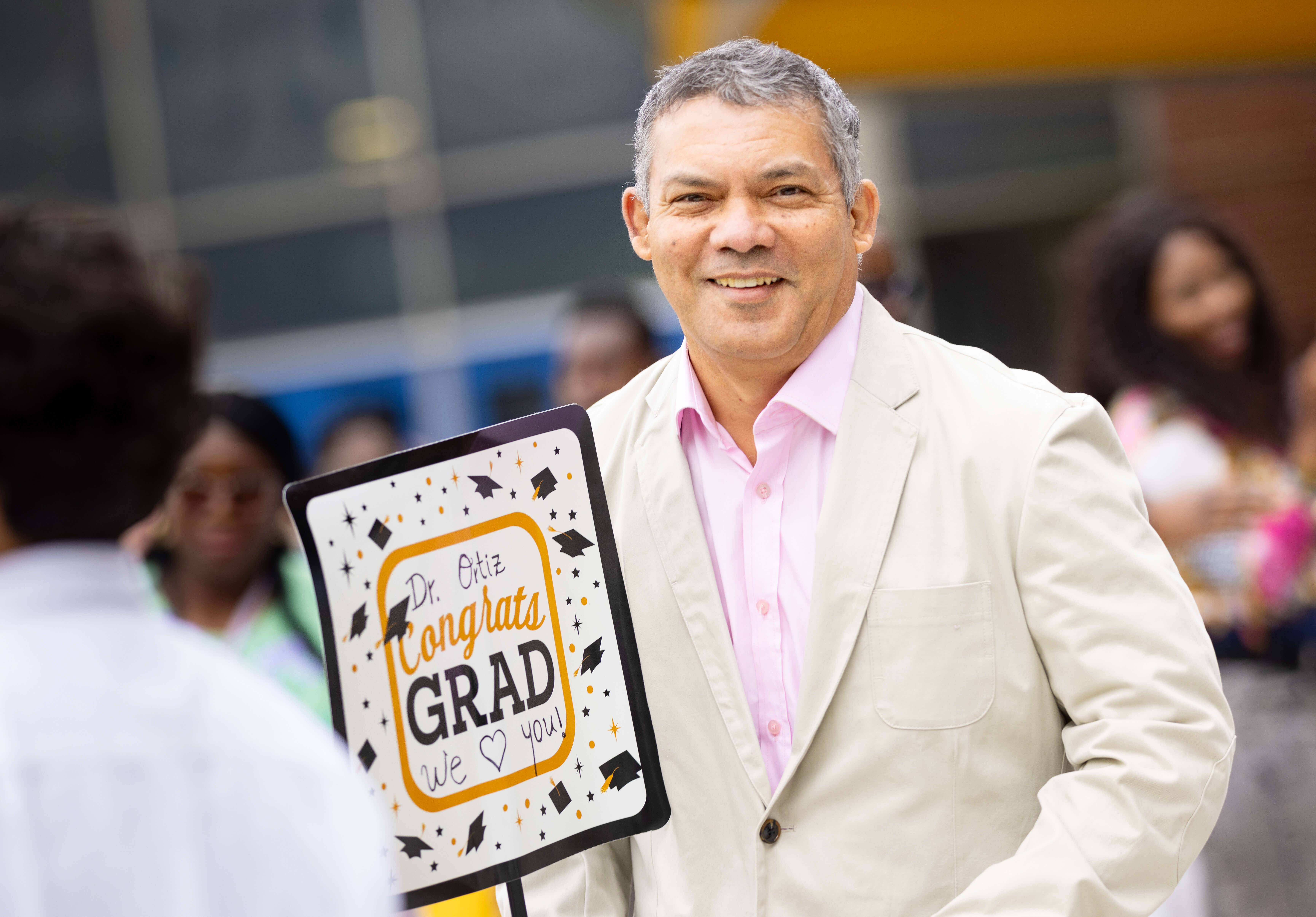 Excited father poses with a sign that says congrats graduate