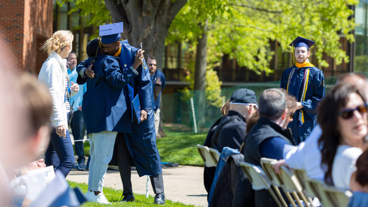 A graduate embraces a loved one after the 2024 commencement ceremony.