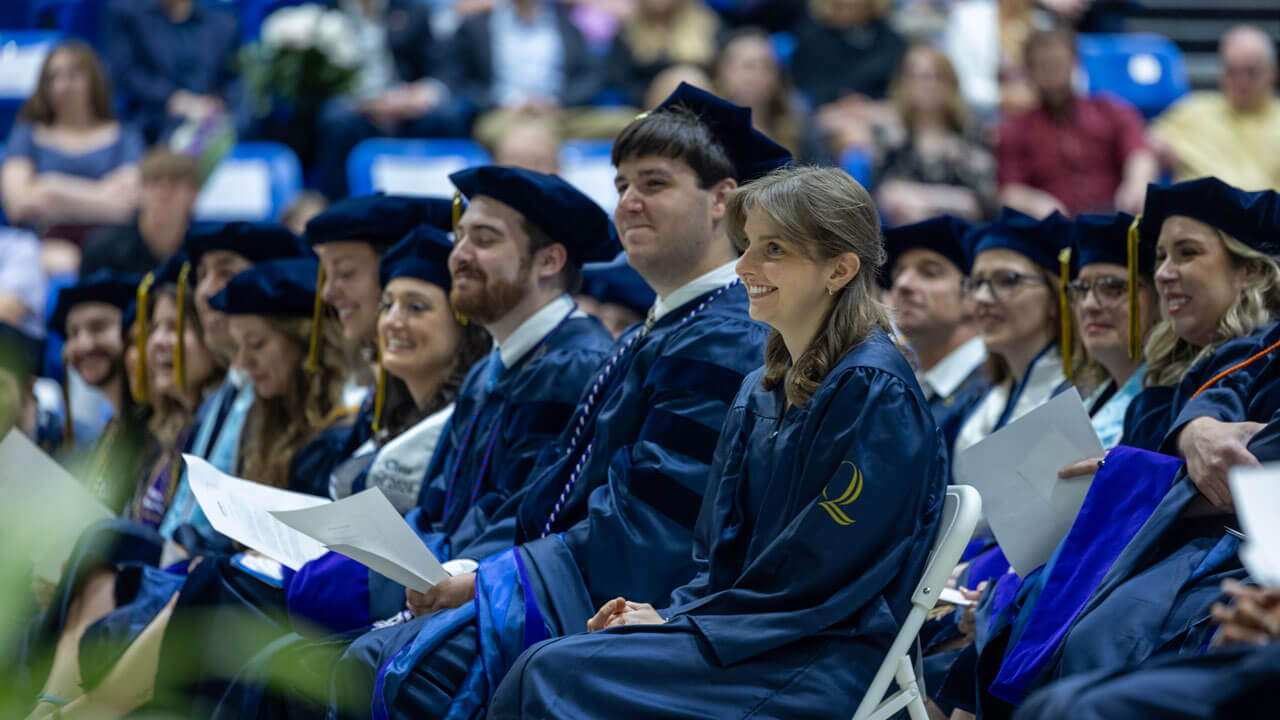 A group of law graduates from the class of 2024 listen attentively after a guest speaker takes the stage.