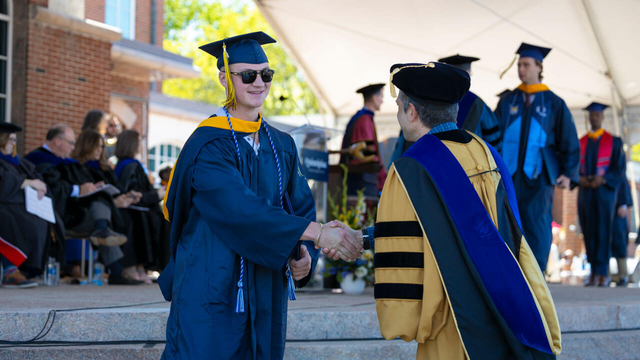 Graduate shaking hands with official after receiving his diploma