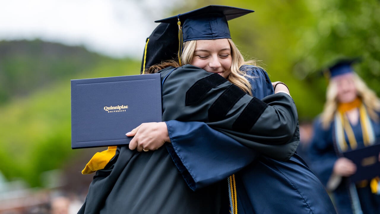 Quinnipiac SOC graduates hugging and showing off their degree