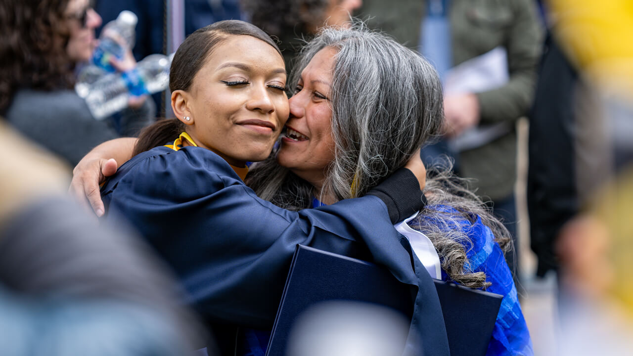 A graduate's family member cries and embraces her graduate