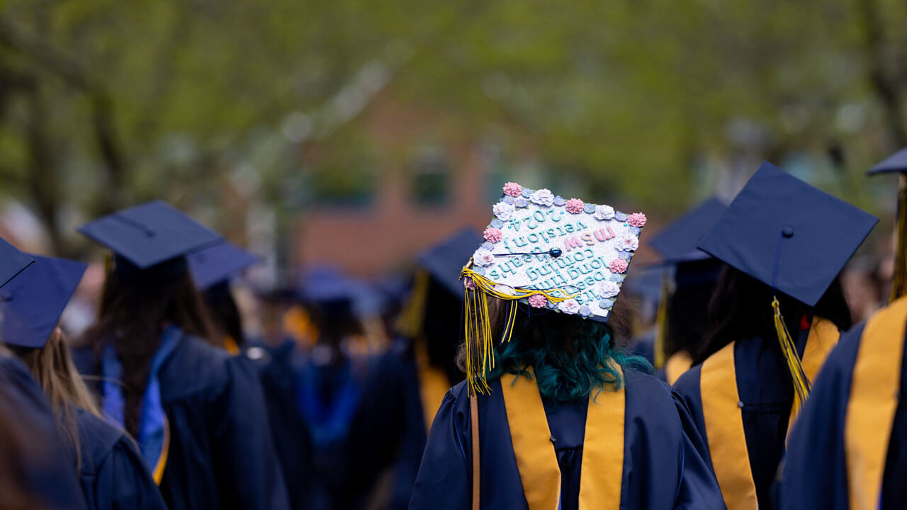 One Health Science graduate wears an ornately decorated graduation cap featuring Taylor Swift lyrics.