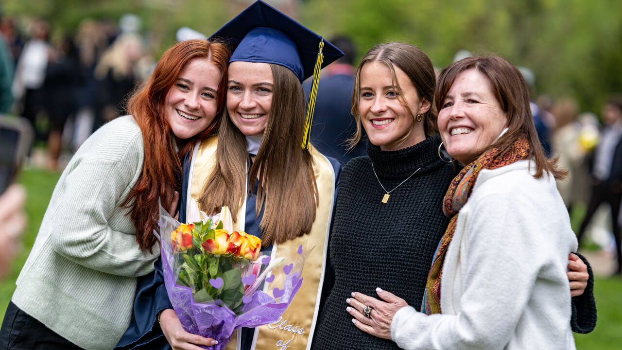 A graduate and three of her guests pose for a photo arm in arm