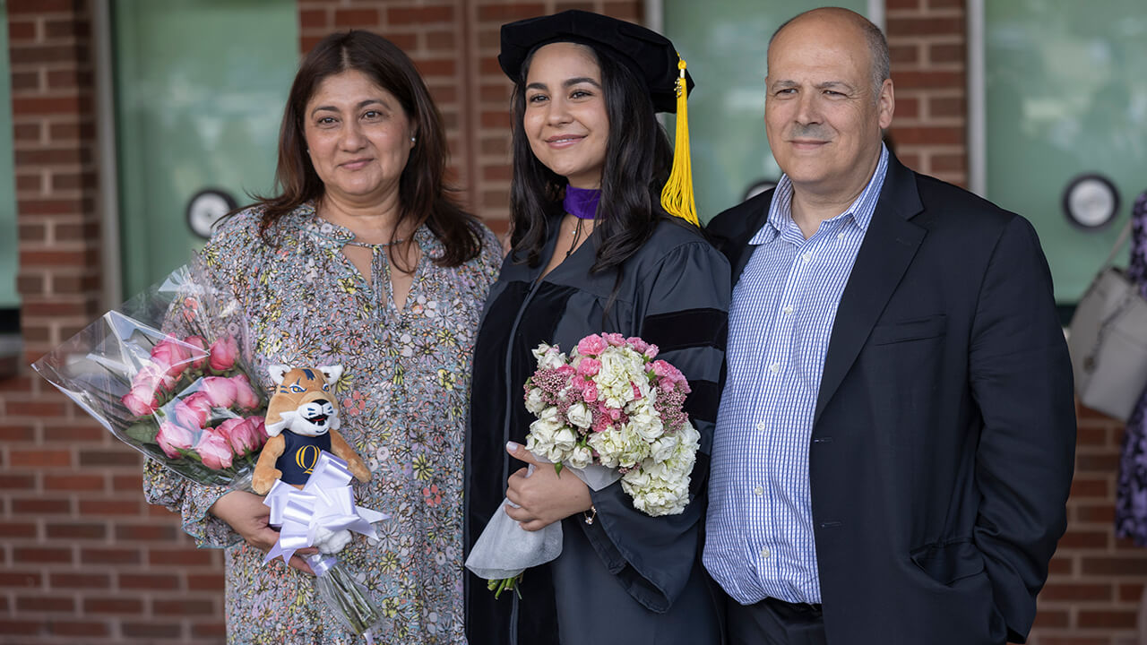 Graduate poses with family and flowers