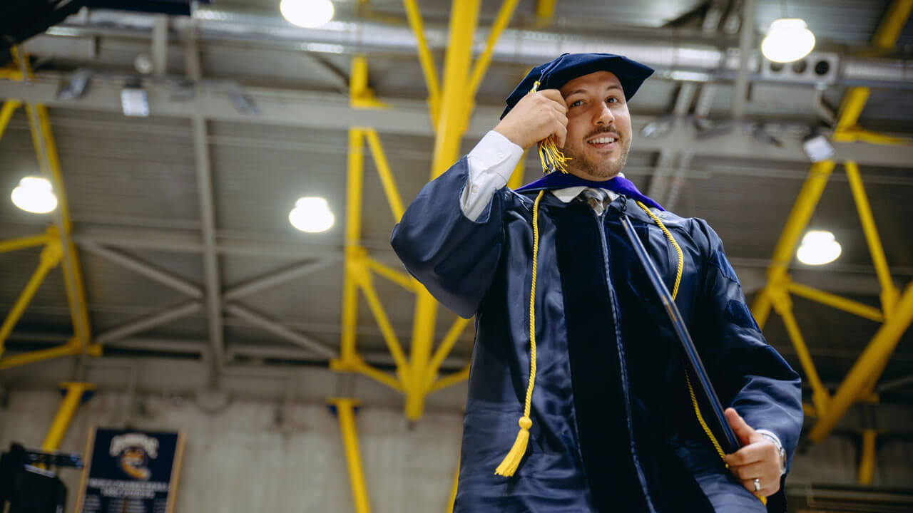 School of Law student holds his tassel and diploma while smiling