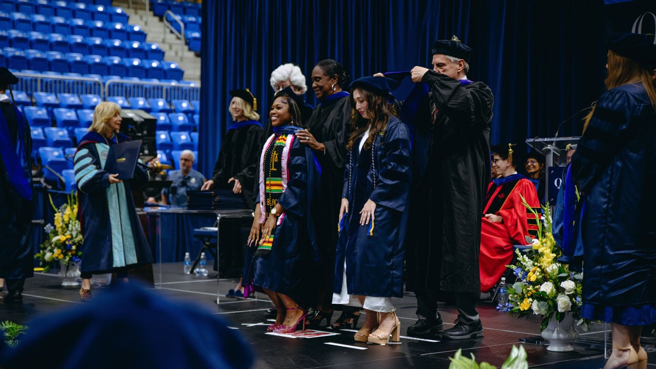 Two Class of 2024 Law students are hooded by faculty