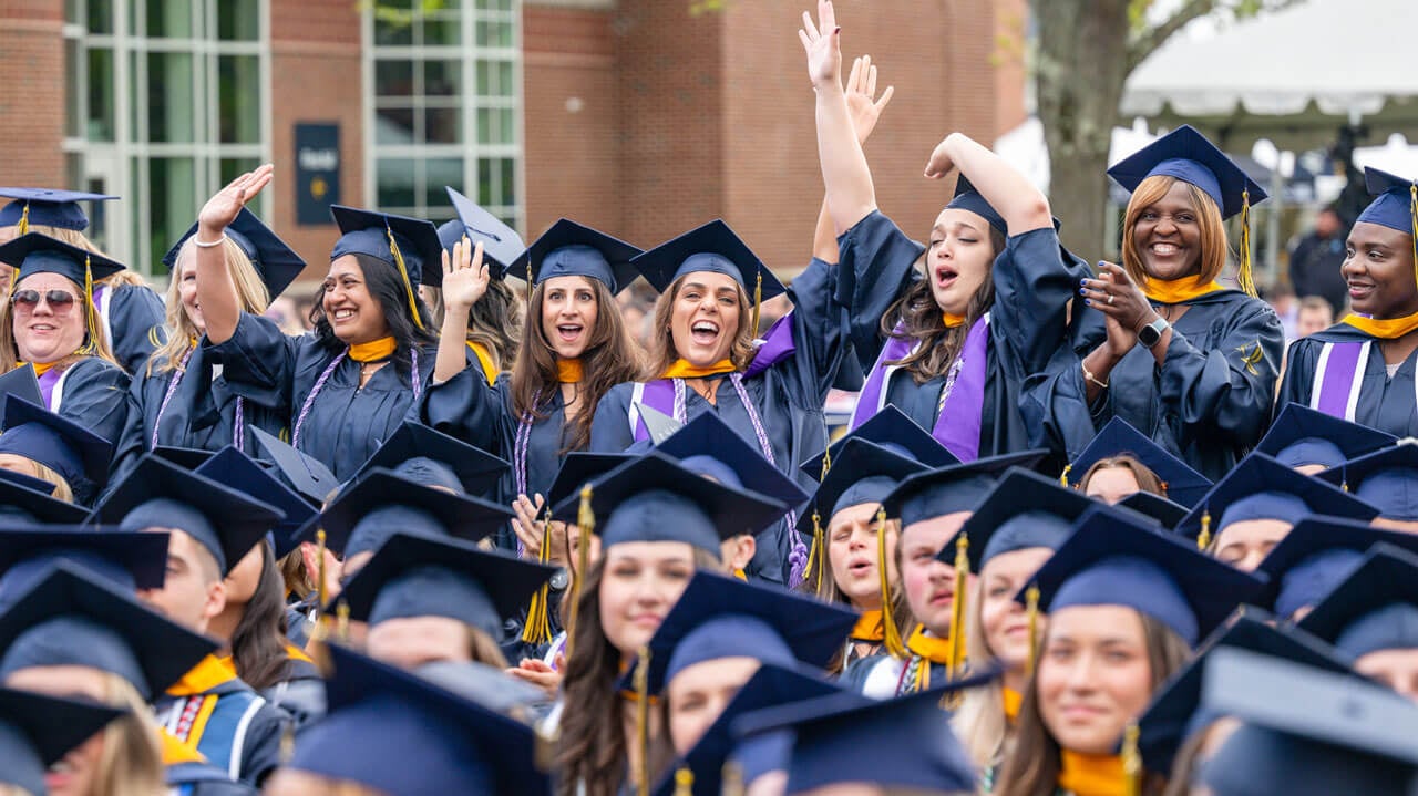 Graduates wave at camera after recieving their degree