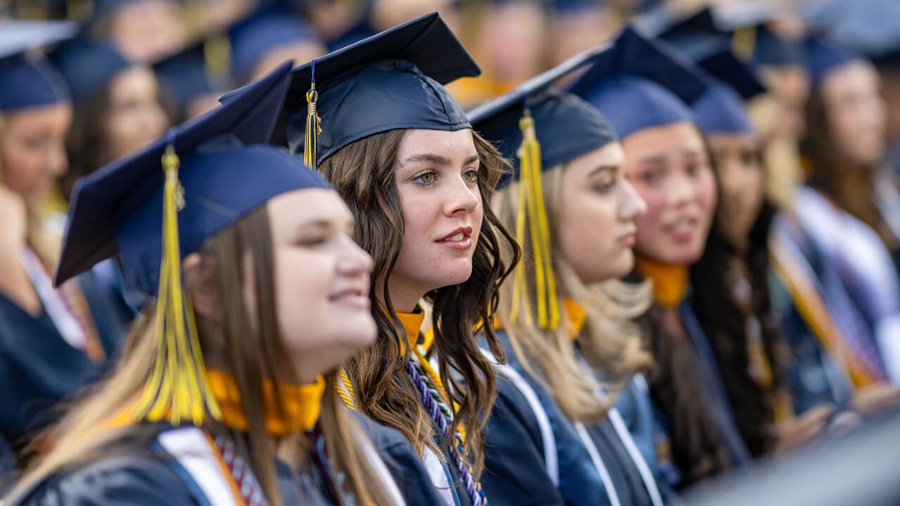 Close up of a row of graduates seated and listening