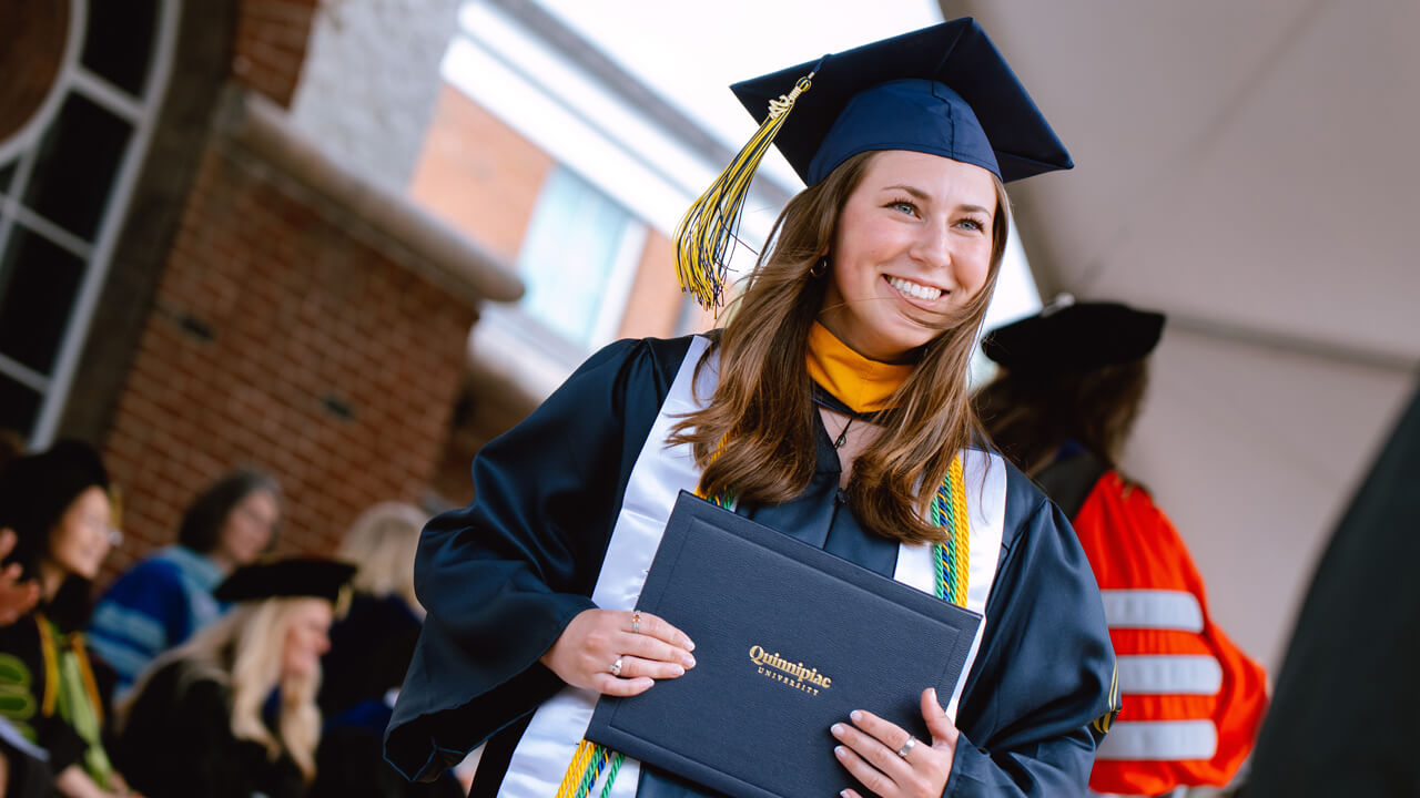 Student smiles holding degree