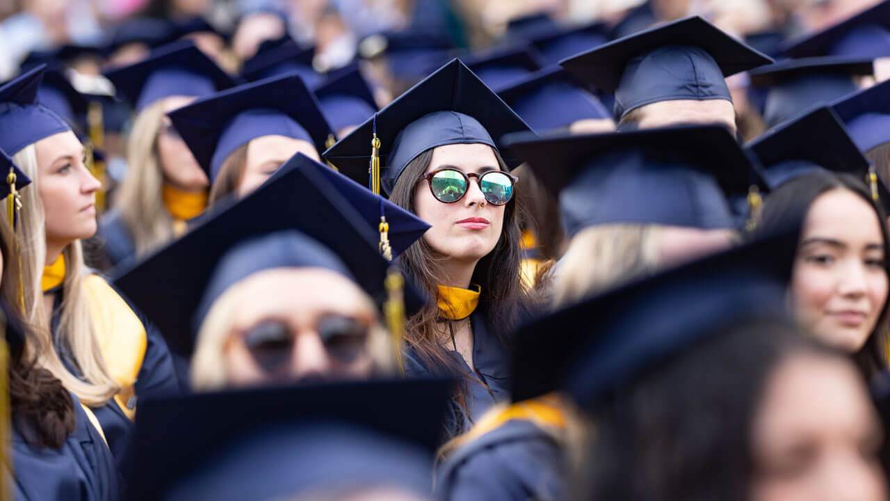 One graduate student can be seen in the crowd donning a pair of colorful sunglasses.