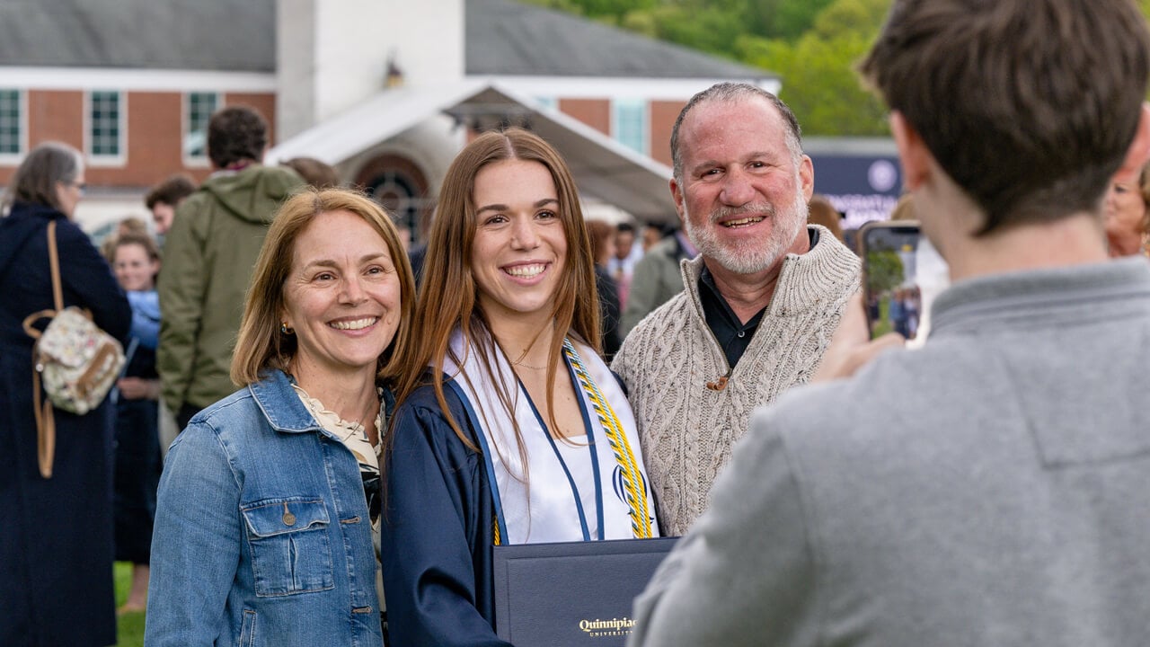 A graduate and her guests pose arm in arm as someone takes their photo