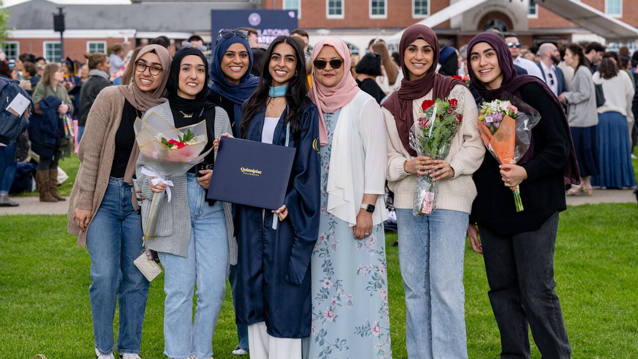 A graduate stands with her group of guests for a photo
