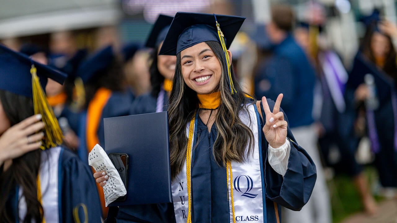 graduate holds up a peace sign