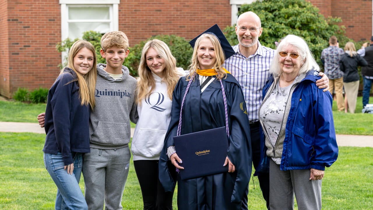 A graduate poses with her diploma for a photo with her family