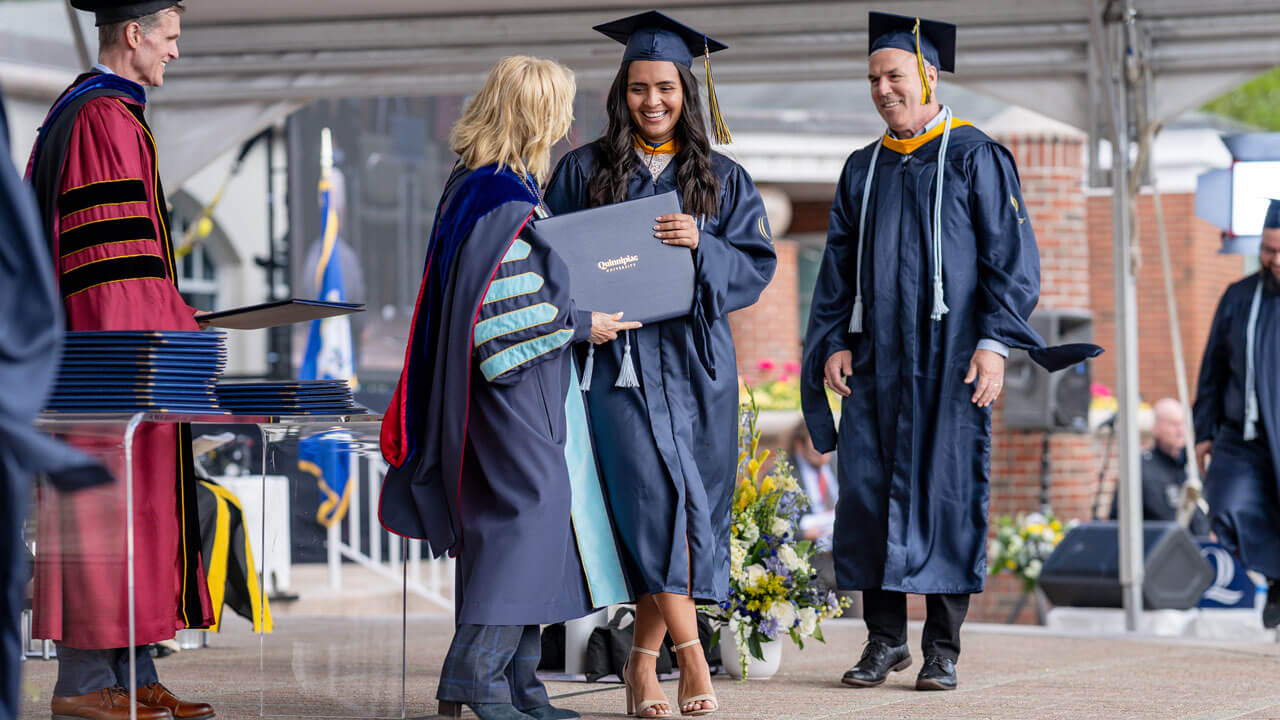Quinnipiac graduate accepting her diploma from President Judy Olian