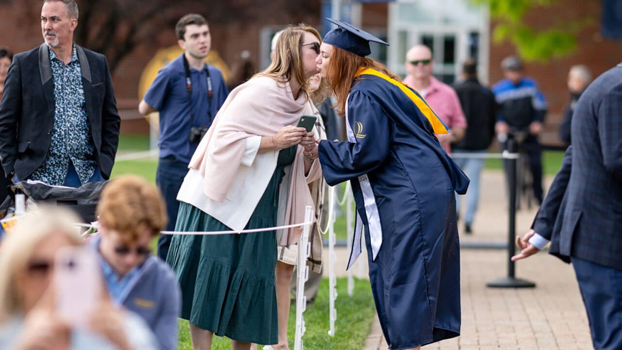 graduate exchanges kisses with crowd member