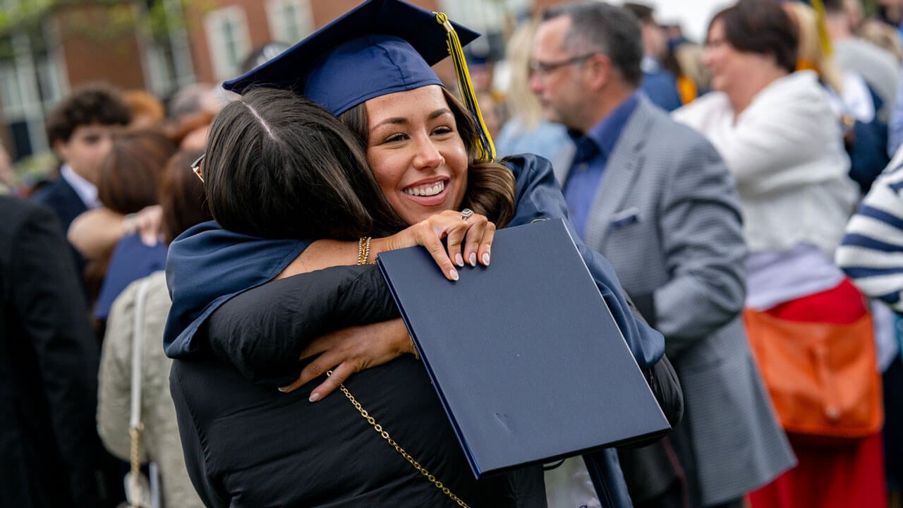 Quinnipiac graduate hugs their family