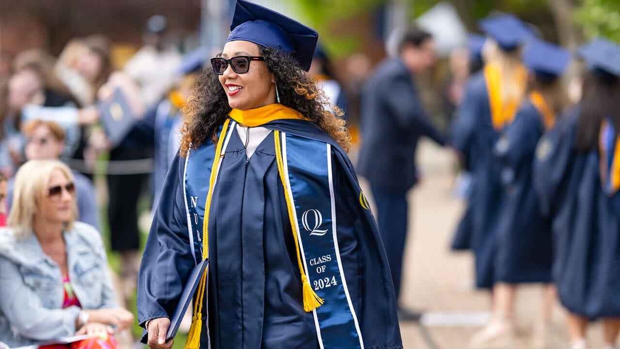 graduate smiles while walking with diploma