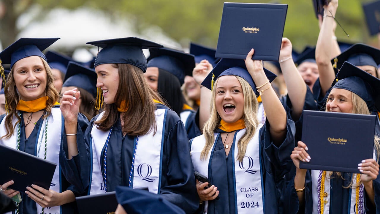 graduates smile with their diplomas