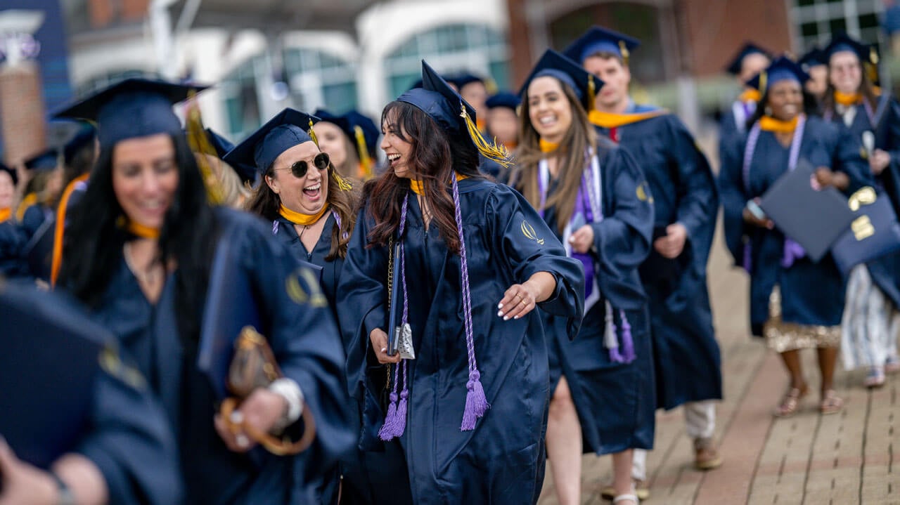 Quinnipiac graduates laughing and walking together