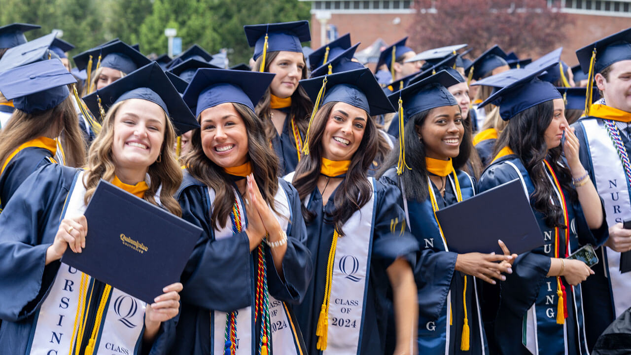 nursing graduates smile and pose with their diplomas