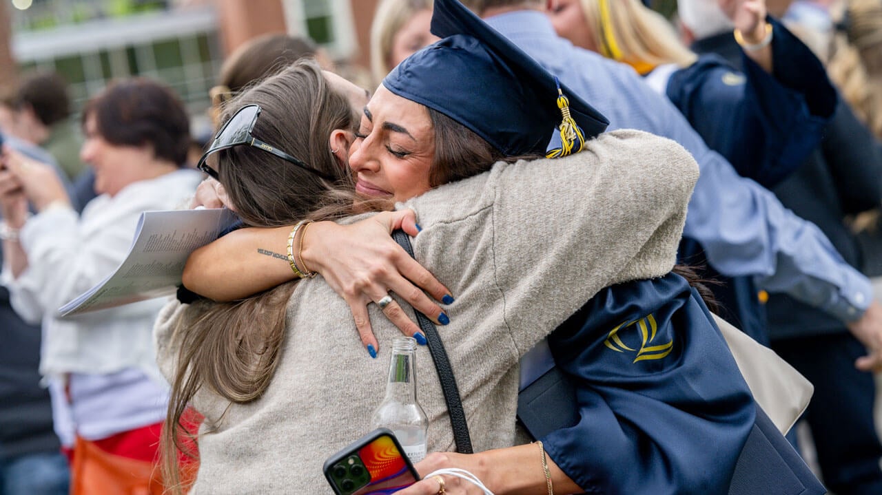Quinnipiac graduate hugs their family member