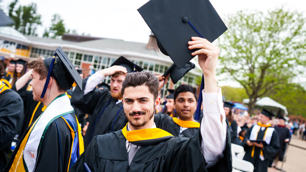 Graduate holds up his cap to celebrate Commencement