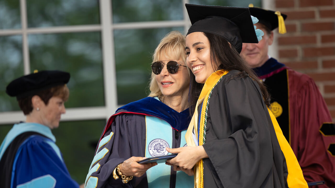 President Olian poses for a photo with a graduate on the Commencement stage