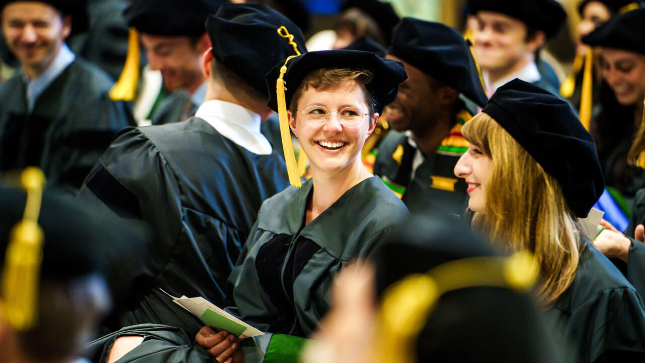 A medical graduate student smiles in the crowd during commencement