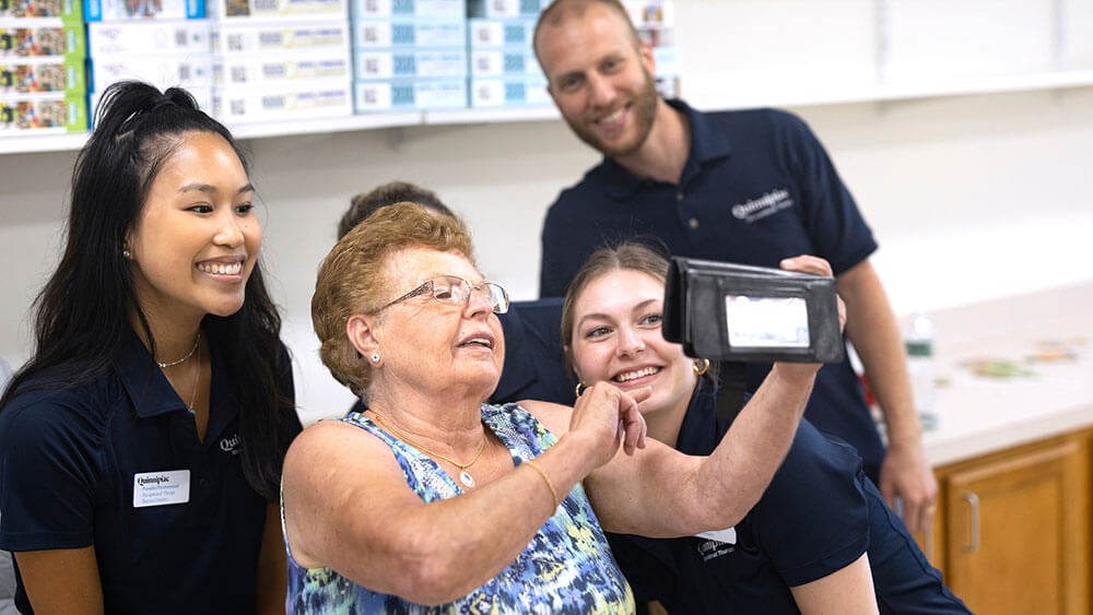 Three Quinnipiac students take a selfie with a senior citizen while volunteering at a senior center