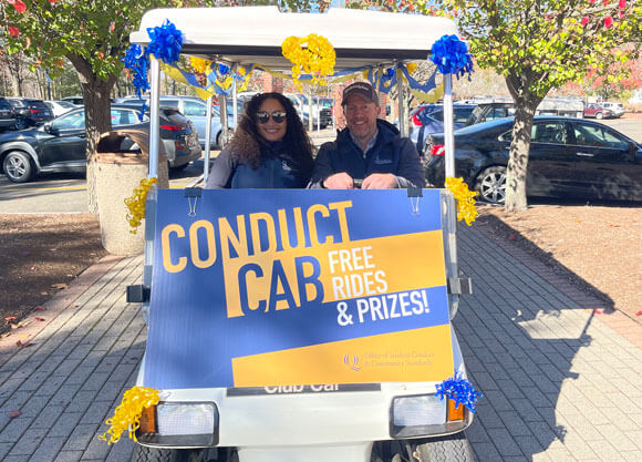 Stephen Sweet and Steffany Almanzar smile in conduct cab while driving around campus