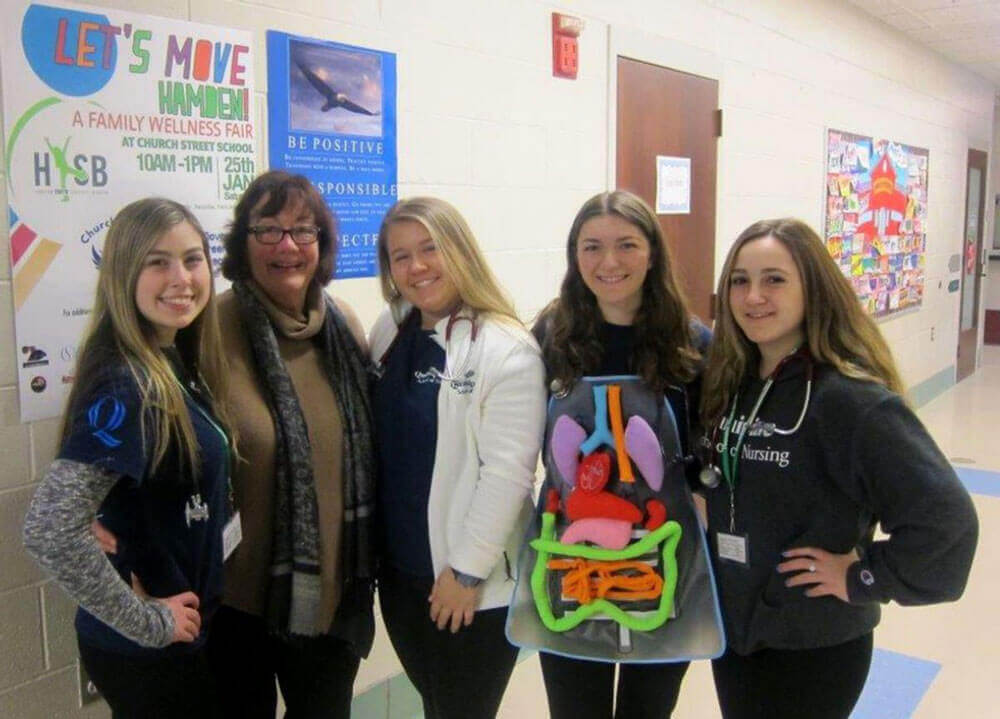 Four female nursing students stand with their female professor.