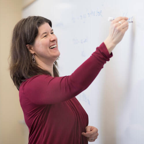 Professor Catherine Solomon writes on a white board