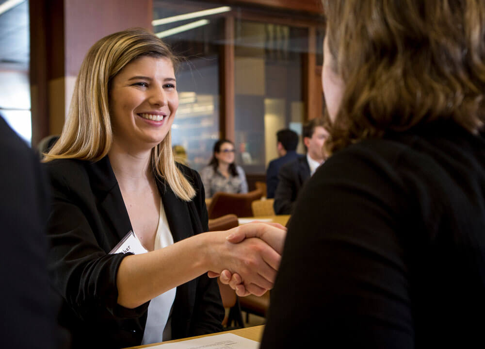 Student shakes hands with an alumni at a networking event