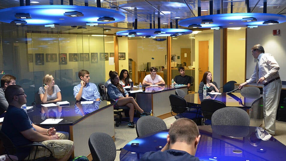 A full class in session in the Media Innovations Classroom with blue light fixtures