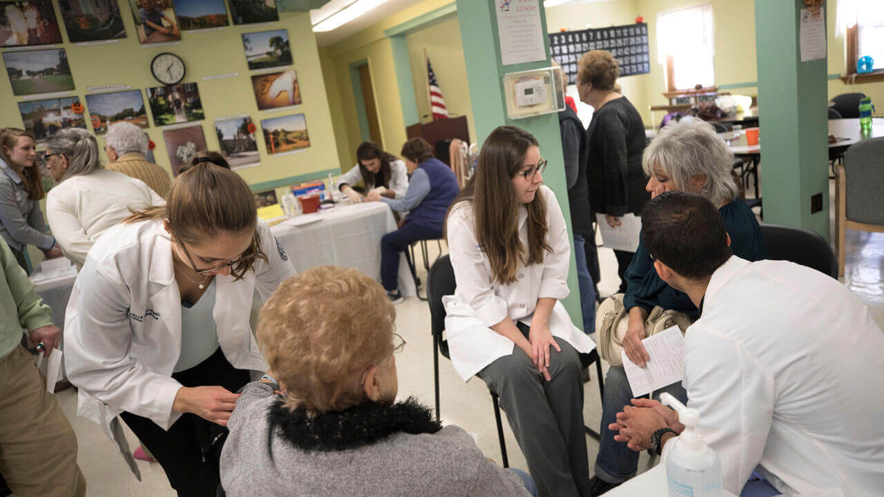 A group of students speak with patients during a health fair