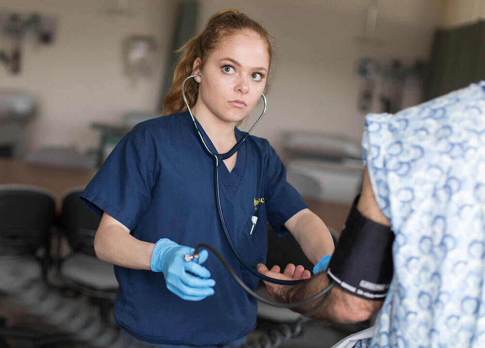 A nursing student takes a patient's blood pressure