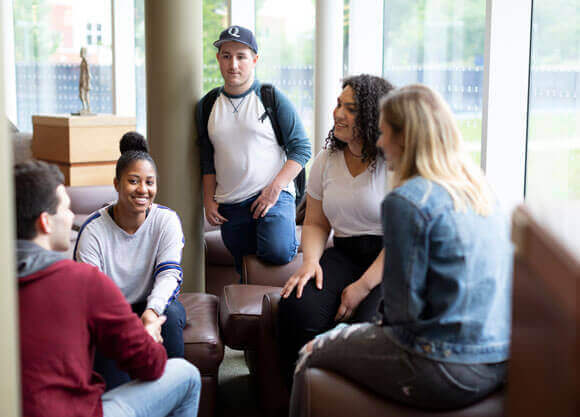 A group of undergraduate students talk together in the library